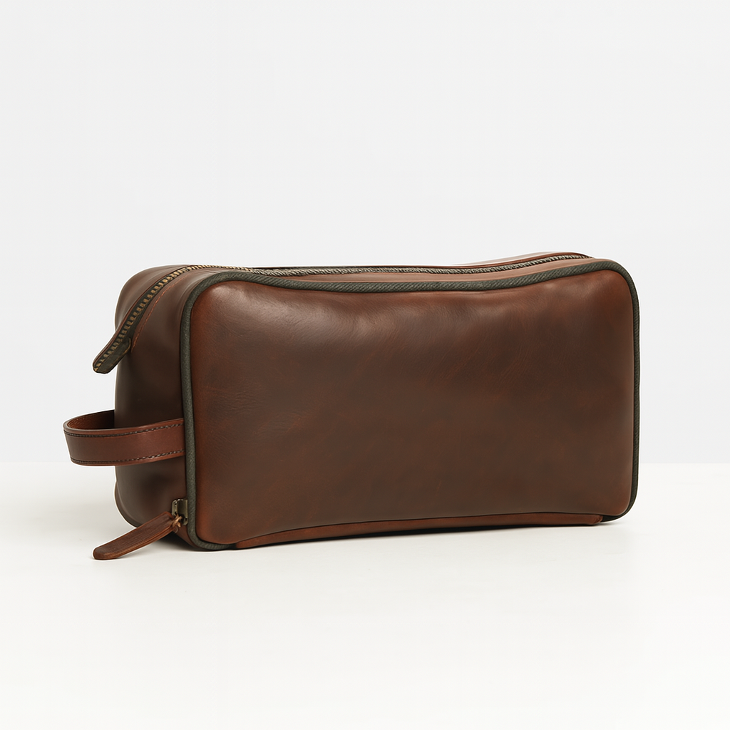 Side view of brown leather toiletry bag with green piping detail